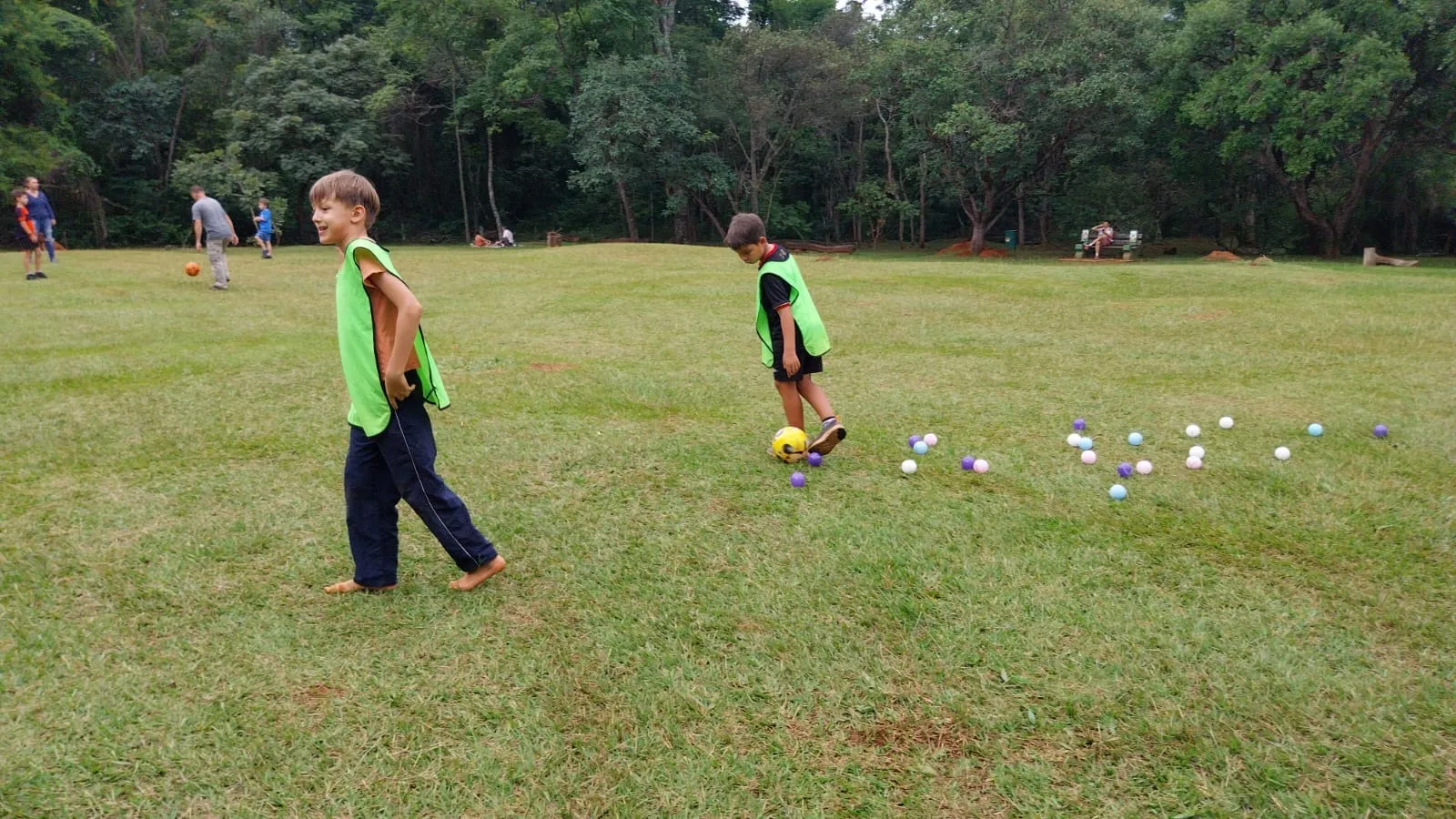 Crianças brincando livres em um amplo gramado em meio à natureza no Oásis