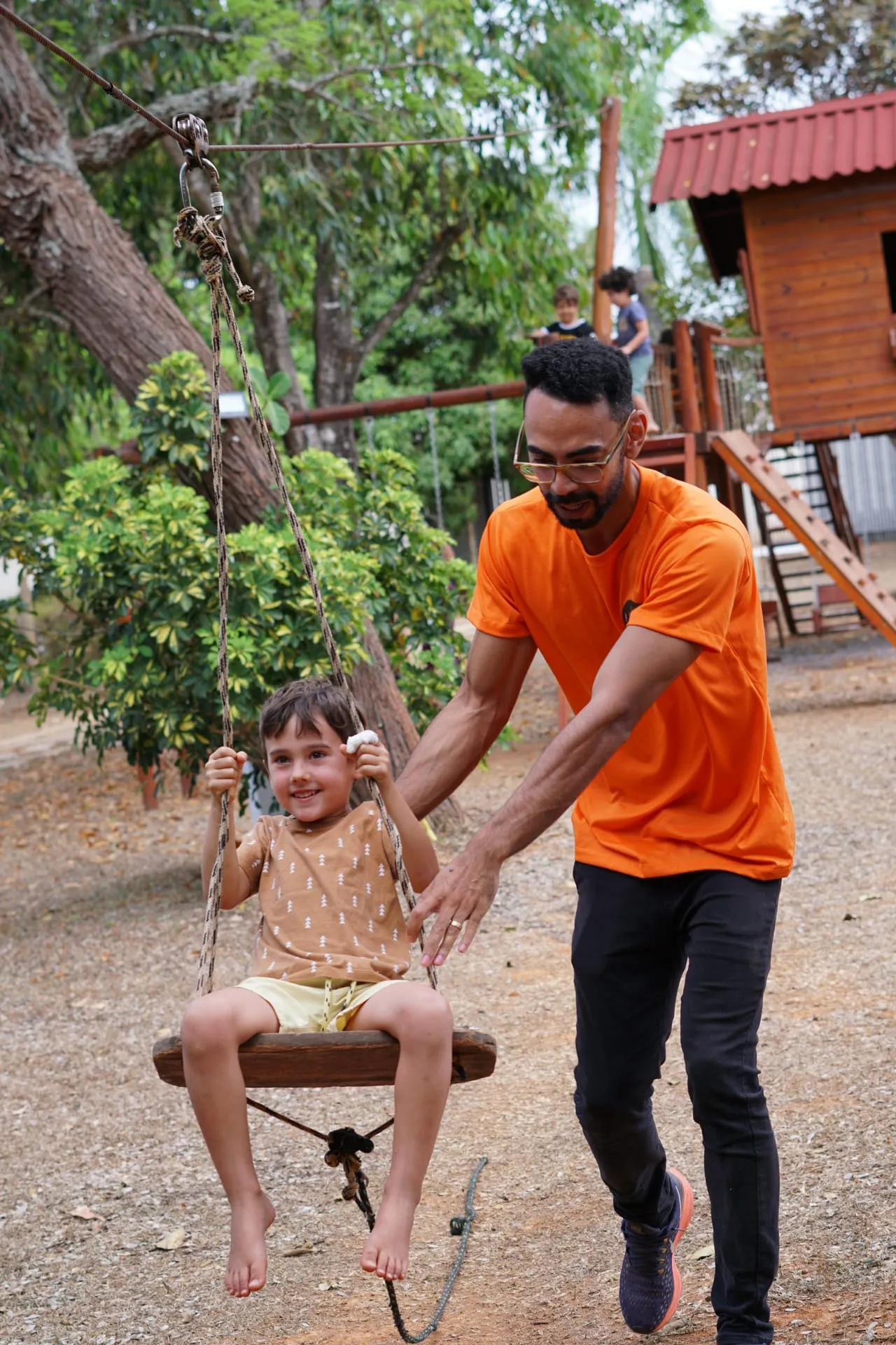 Educador do Oásis empurrando uma criança no balanço